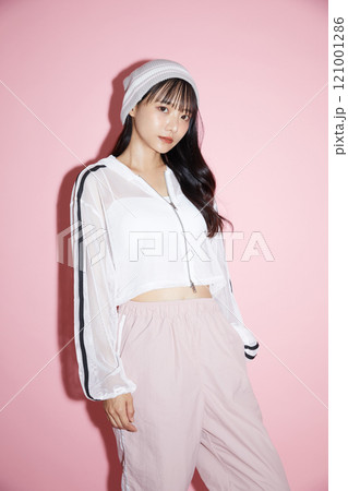 ピンク背景で撮影をしたスポーティな服装をした若い女性のキュートなポートレート 121001286