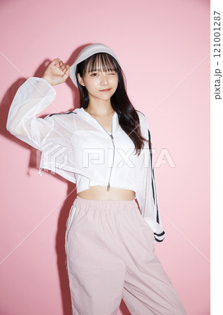ピンク背景で撮影をしたスポーティな服装をした若い女性のキュートなポートレート 121001287