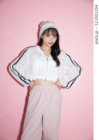 ピンク背景で撮影をしたスポーティな服装をした若い女性のキュートなポートレート 121001294