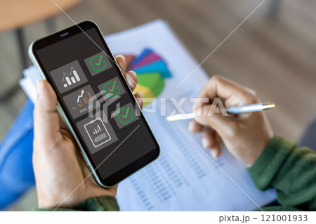 Using mobile smartphone, Business woman working with balance sheet of accounting for calaulating finance, tax, accounting, statistics and analytic research concept. Using mobile smartphone, Business woman working with balance sheet of accounting for calaulating finance, tax, accounting, statistics and analytic research concept. 121001933