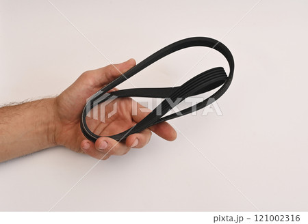 the belt of the car generator. spare parts on a white background in the mechanic's hand 121002316