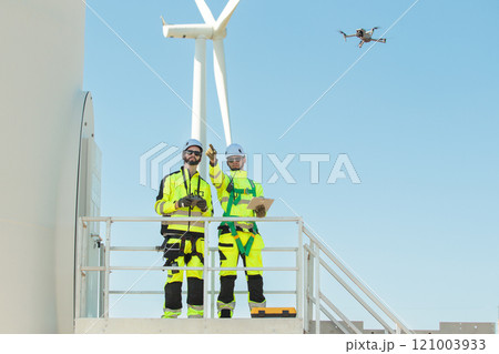 Team of electrical engineer is perform the inspection and maintenance of electric generating windmill turbine. Team of professional electrical engineers in fully safety suit are working and discussing Team of electrical engineer is perform the inspection and maintenance of electric generating windmill turbine. Team of professional electrical engineers in fully safety suit are working and discussing 121003933