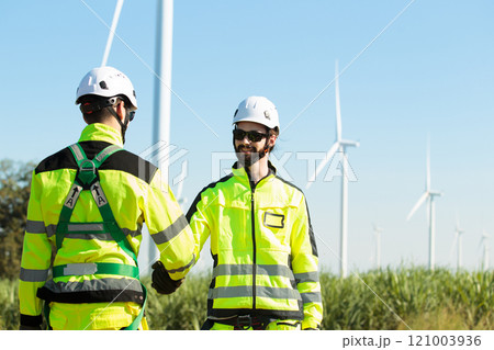 Team of electrical engineer is perform the inspection and maintenance of electric generating windmill turbine. Team of professional electrical engineers in fully safety suit are working and discussing 121003936