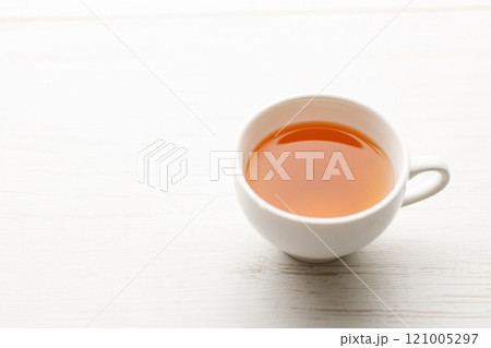 Cup of hot tea blended from rooibos, spearmint, apple, baobab on white wooden table. 121005297