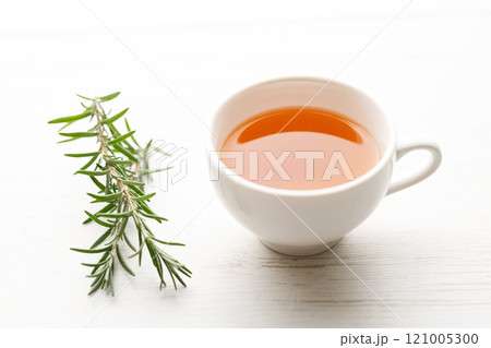 Cup of hot tea blended from rooibos, spearmint, apple, baobab on white wooden table. 121005300