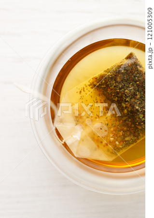 Cup of hot tea blended from rooibos, spearmint, apple, baobab on white wooden table. 121005309