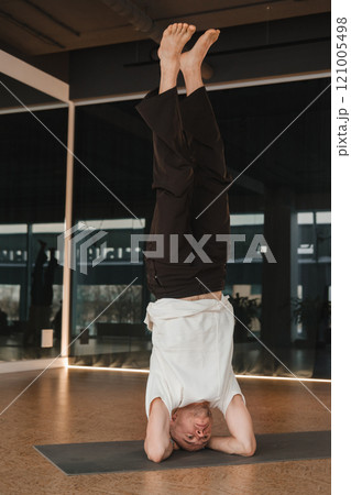 An athletic young man does exercises in the fitness room. A professional guy does yoga in the gym 121005498