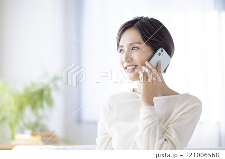 ライフスタイル ソファーに座りスマホで通話する女性 ライフスタイル ソファーに座りスマホで通話する女性 121006568