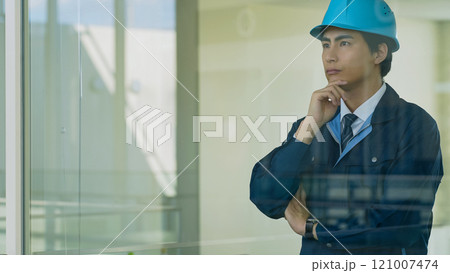 建物の中でガラス越しに考える男性作業員 121007474