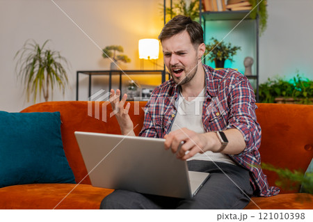 Upset man using laptop having anxiety and stress loss bad lottery game results news at home room 121010398