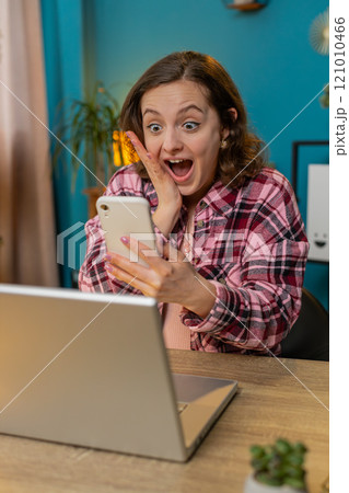 Amazed business woman girl working on smartphone shocked by sudden game win victory lottery jackpot Amazed business woman girl working on smartphone shocked by sudden game win victory lottery jackpot 121010466
