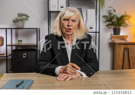 Aggressive Caucasian senior businesswoman gesturing hands blaming scolding for failure at table Aggressive Caucasian senior businesswoman gesturing hands blaming scolding for failure at table 121010652