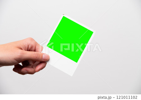 photo frame in girl's hands. instant printed photo in female hand close-up, layout for your advertising. snapshot of happy moment in life green screen 121011102