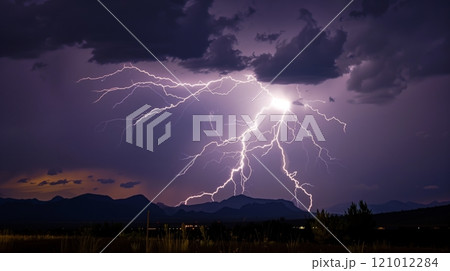 A lightning bolt silhouettes a jagged mountain range, casting an eerie glow on the dark horizon. 121012284