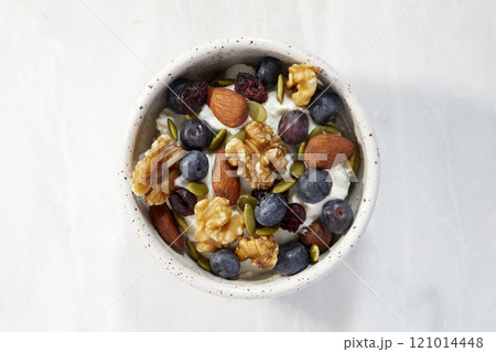 Overhead view of bowl of yogurt with berries and nuts 121014448