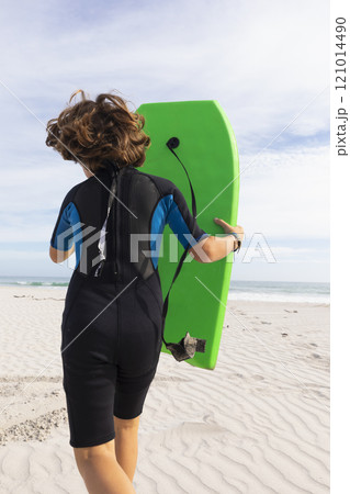 South Africa, Hermanus, Rear view of boy running on beach with body board 121014490