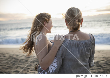 Rear view of mother and teenage daughter on beach 121014603