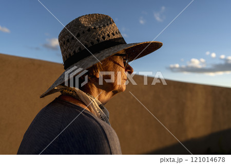Usa, New Mexico, Santa Fe, Woman in straw hat standing against adobe wall in High Desert Usa, New Mexico, Santa Fe, Woman in straw hat standing against adobe wall in High Desert 121014678