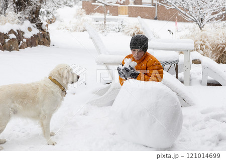 Boy with his dog building snowman Boy with his dog building snowman 121014699