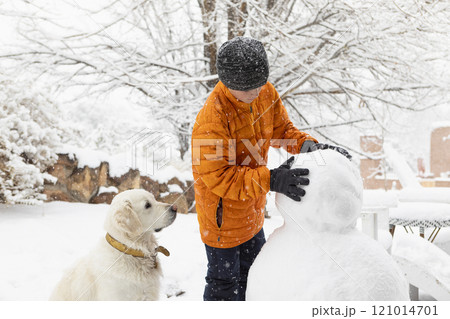 Boy with his dog building snowman Boy with his dog building snowman 121014701