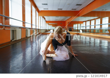 Ballerina sitting on floor in ballet studio 121014917