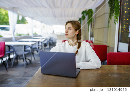 Pensive woman with laptop at cafe table Pensive woman with laptop at cafe table 121014956