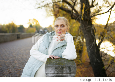 Portrait of woman leaning on wall by river in autumn 121015210