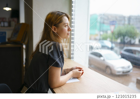 Woman leaning on window sill and looking through window Woman leaning on window sill and looking through window 121015235