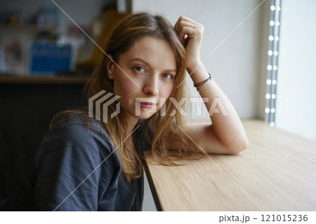 Portrait of woman leaning on window sill Portrait of woman leaning on window sill 121015236