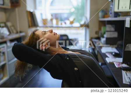 Woman leaning on chair in office Woman leaning on chair in office 121015240