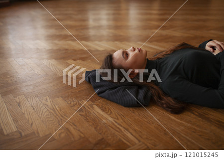 Pensive woman lying on parquet floor 121015245