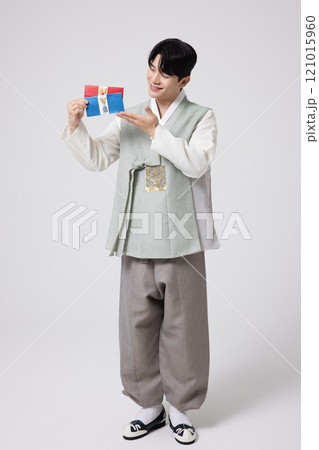 Portrait of a young man wearing hanbok and holding a luxury gift certificate 121015960