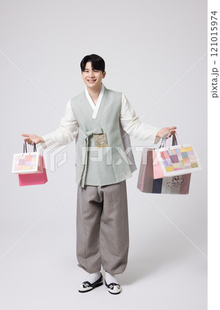 A young man wearing a hanbok and holding shopping bags in both hands A young man wearing a hanbok and holding shopping bags in both hands 121015974