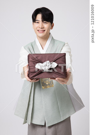 A young man wearing a hanbok and holding a carefully prepared holiday gift 121016009