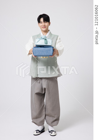 Portrait of a young man wearing hanbok and holding a luxurious holiday gift 121016062