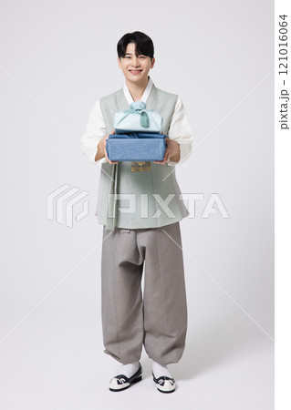 Portrait of a young man wearing hanbok and holding a luxurious holiday gift 121016064
