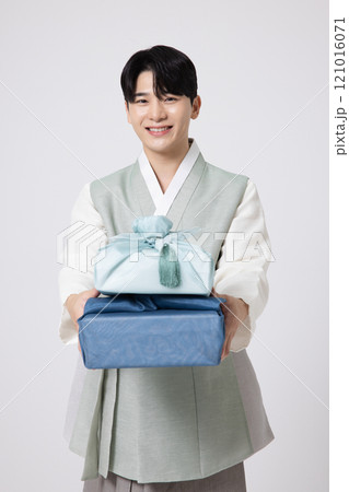 Portrait of a young man wearing hanbok and holding a luxurious holiday gift Portrait of a young man wearing hanbok and holding a luxurious holiday gift 121016071