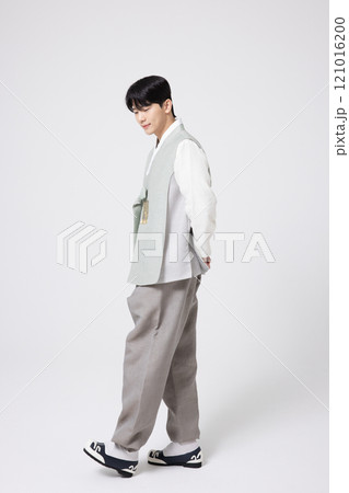 A young man wearing a hanbok and walking with his back behind him. 121016200