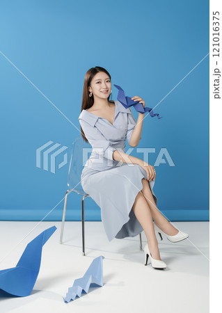 A woman sitting and posing in front of a blue snake folded out of paper A woman sitting and posing in front of a blue snake folded out of paper 121016375