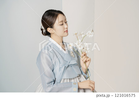 A beautiful woman wearing a luxurious and elegant hanbok is standing holding a flower A beautiful woman wearing a luxurious and elegant hanbok is standing holding a flower 121016575