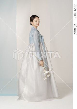 A beautiful woman wearing a luxurious and elegant hanbok is standing holding a flower A beautiful woman wearing a luxurious and elegant hanbok is standing holding a flower 121016586