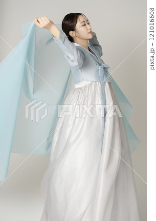 A beautiful woman wearing a luxurious and elegant Hanbok dancing with a blue cloth wrapped around her. 121016608