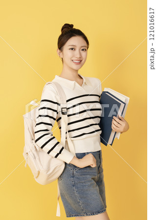 A college student wearing casual clothes and posing with a book A college student wearing casual clothes and posing with a book 121016617