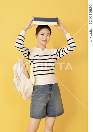 A college student wearing casual clothes and posing with a book A college student wearing casual clothes and posing with a book 121016620