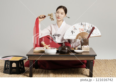 A young shaman sitting with a shamanic bell and a fan in front of a table with shamanic tools spread out. 121016742