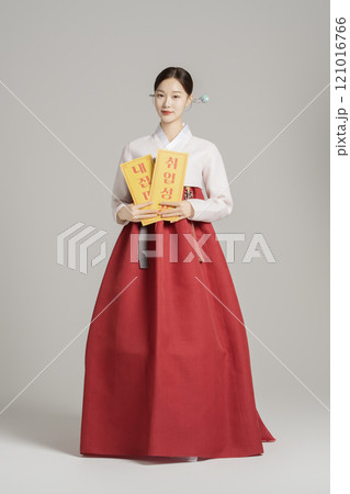 A woman in her 20s wearing a hanbok, wearing a colorful hairpin, and posing while holding an amulet. A woman in her 20s wearing a hanbok, wearing a colorful hairpin, and posing while holding an amulet. 121016766