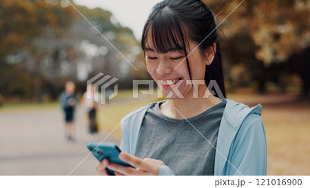 Smile, woman and typing with phone of fitness outdoor, communication and research of exercise application. Happy, athlete and mobile for gym membership, training schedule and workout routine in Japan 121016900