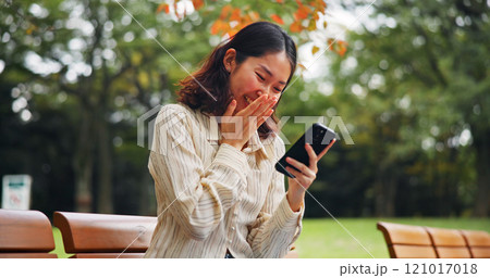 Woman, laugh and outdoor with phone for social media, funny meme and humor story in Tokyo. Japanese girl, mobile and happy in park for app notification, connectivity and streaming comedy on bench 121017018