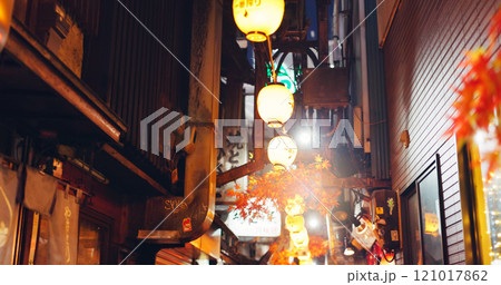 Night, lights and street market in city of japan on vacation for shopping, travel destination or festival. Culture, traditional holiday and lamps with alley in outdoor for urban, tourism and heritage 121017862