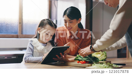 Mom, girl and tablet in kitchen with father, cooking and happy with streaming, recipe or teaching in family home. People, mother and daughter with touchscreen, food and meal prep at house in Japan 121017878